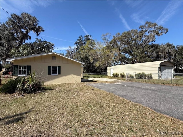 view of side of home featuring a garage, an outdoor structure, and a lawn