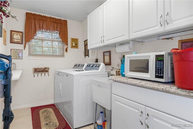 washroom featuring light tile patterned flooring, cabinets, and washing machine and dryer