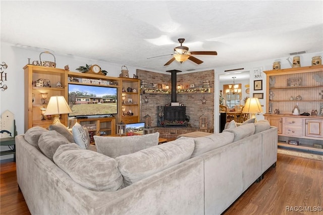 living room with wood-type flooring, ceiling fan with notable chandelier, a textured ceiling, and a wood stove