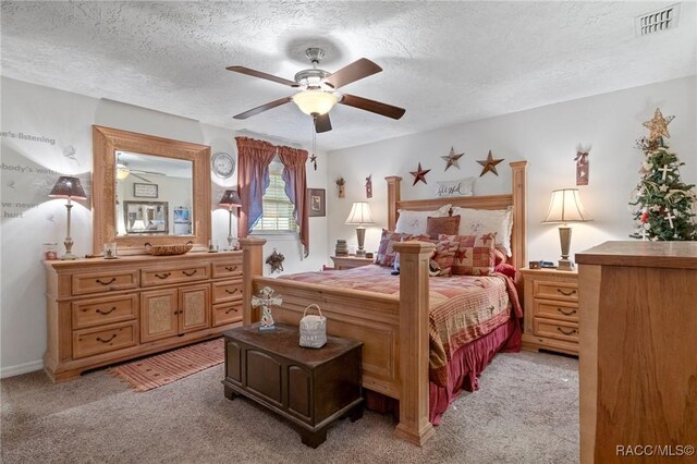 bedroom featuring ceiling fan, light colored carpet, and a textured ceiling