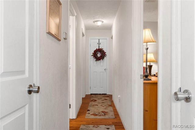 corridor with light hardwood / wood-style flooring and a textured ceiling