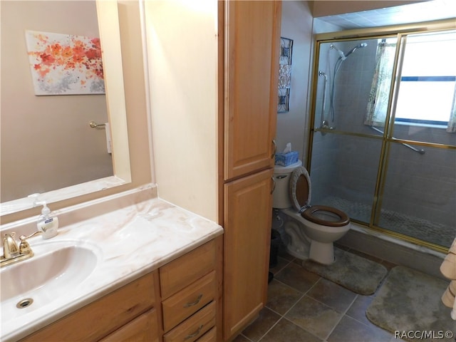 bathroom featuring tile patterned flooring, vanity, toilet, and a shower with shower door