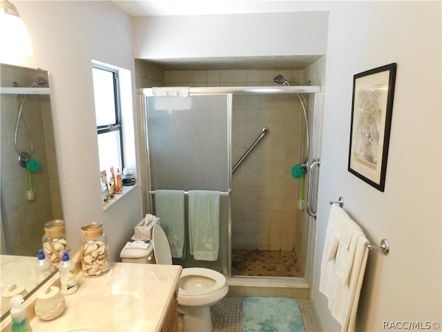 bathroom with tile patterned floors, vanity, an enclosed shower, and toilet