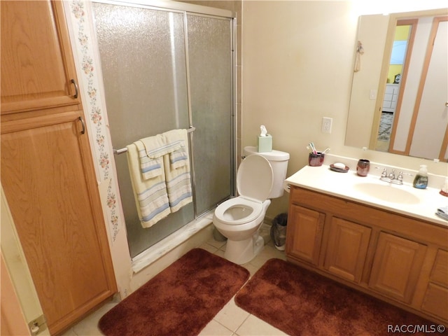 bathroom featuring tile patterned flooring, vanity, a shower with shower door, and toilet