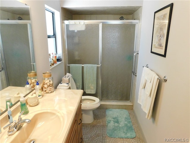 bathroom with tile patterned flooring, vanity, a shower with shower door, and toilet