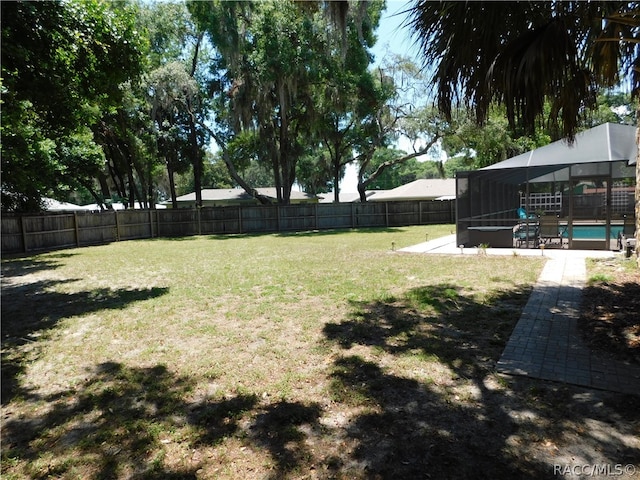 view of yard featuring a fenced in pool, glass enclosure, and a patio