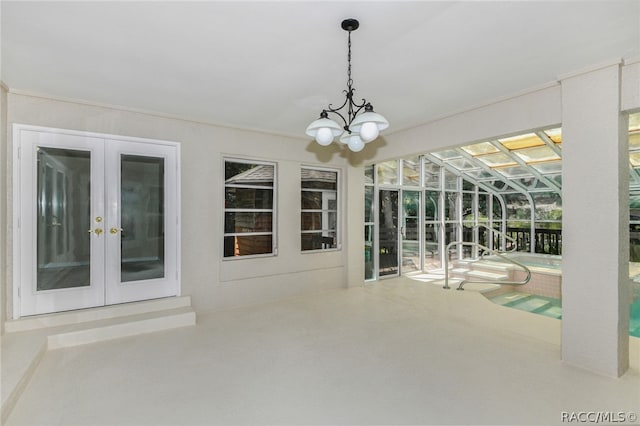 unfurnished sunroom with french doors and a notable chandelier