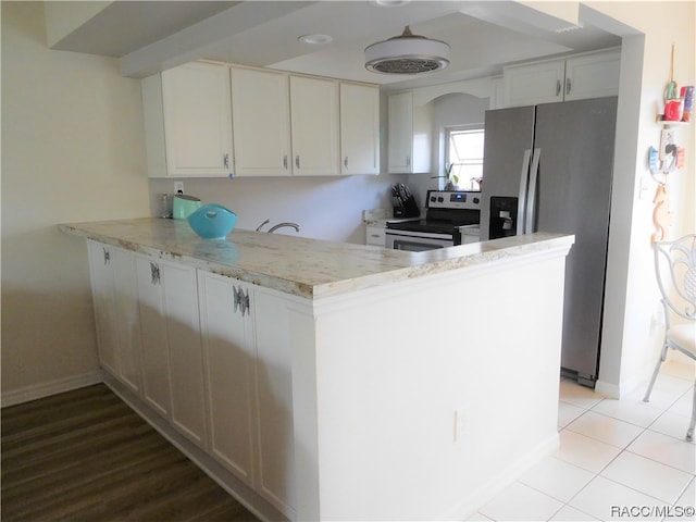 kitchen featuring white cabinets, light tile patterned floors, kitchen peninsula, and appliances with stainless steel finishes