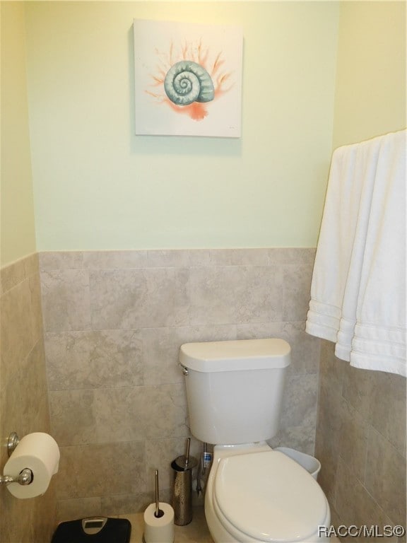 bathroom featuring tile walls and toilet