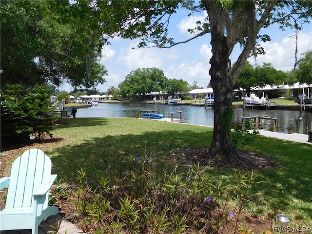 view of dock with a lawn and a water view