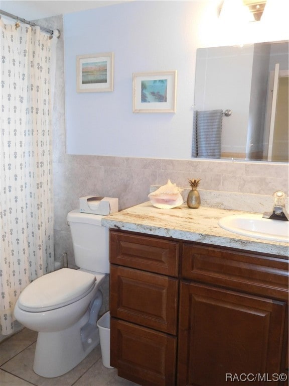 bathroom with tile patterned floors, walk in shower, vanity, tile walls, and toilet