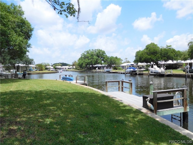 view of dock with a water view and a lawn