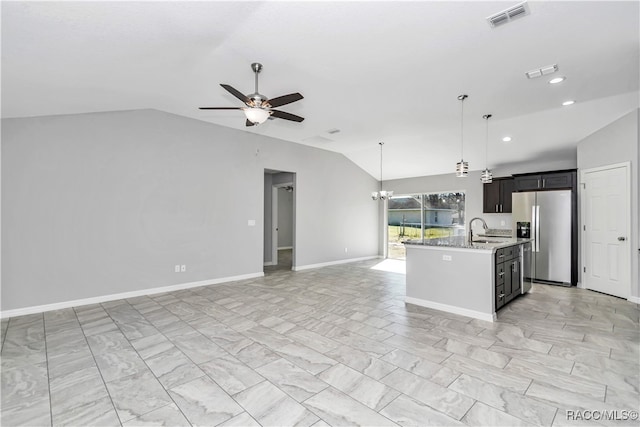 kitchen with pendant lighting, an island with sink, lofted ceiling, sink, and stainless steel fridge