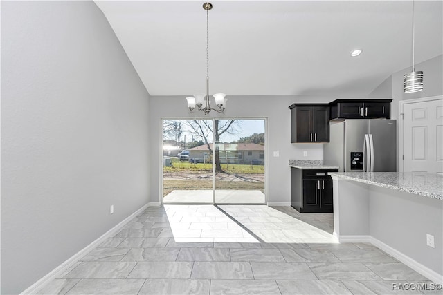 kitchen featuring lofted ceiling, decorative light fixtures, light stone countertops, and stainless steel fridge with ice dispenser