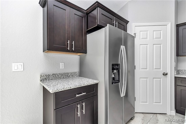 kitchen featuring light stone counters, stainless steel fridge with ice dispenser, and dark brown cabinetry