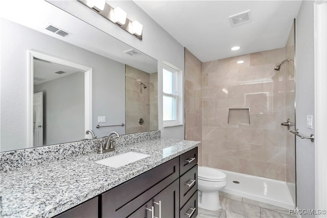 bathroom with vanity, toilet, and tiled shower