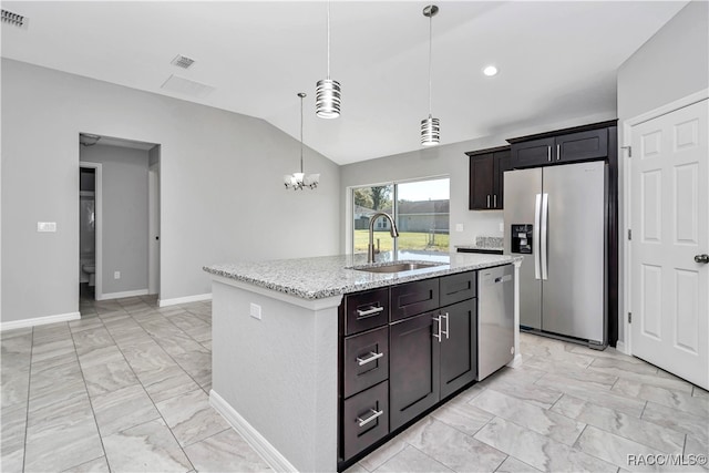 kitchen featuring sink, hanging light fixtures, stainless steel appliances, light stone counters, and an island with sink