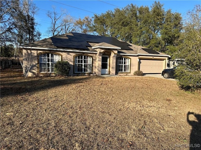 ranch-style home with a garage, a front lawn, and solar panels