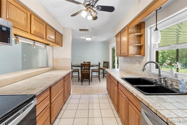 kitchen featuring light tile patterned floors, tasteful backsplash, tile counters, open shelves, and a sink