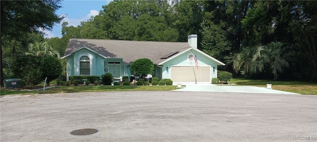 ranch-style house with solar panels, a garage, and a front lawn