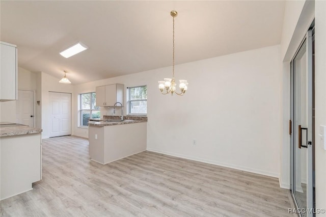 kitchen with pendant lighting, white cabinetry, vaulted ceiling, kitchen peninsula, and light wood-type flooring