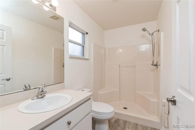 bathroom featuring a shower, wood-type flooring, vanity, toilet, and a textured ceiling