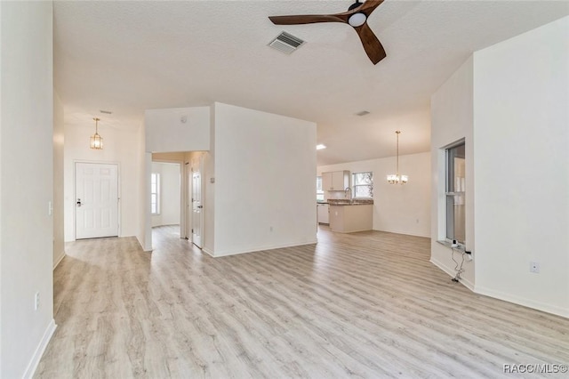 unfurnished living room featuring sink, ceiling fan with notable chandelier, a textured ceiling, and light wood-type flooring