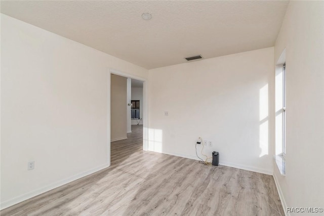 unfurnished room featuring a textured ceiling and light hardwood / wood-style flooring