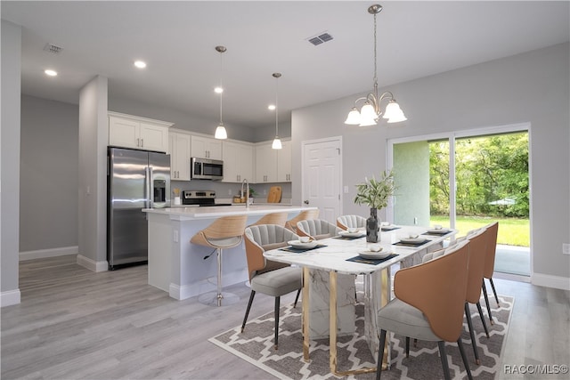 dining area featuring a chandelier, sink, and light hardwood / wood-style floors