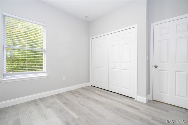 unfurnished bedroom with a closet, light hardwood / wood-style floors, and multiple windows