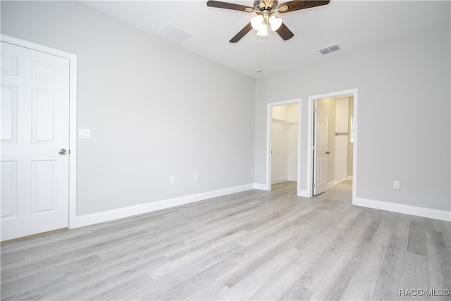 unfurnished bedroom featuring ceiling fan, light hardwood / wood-style floors, and a spacious closet