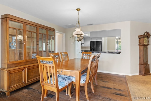 dining space with dark wood-type flooring and an inviting chandelier