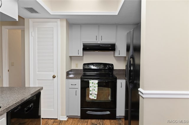 kitchen with black appliances, white cabinets, and hardwood / wood-style flooring