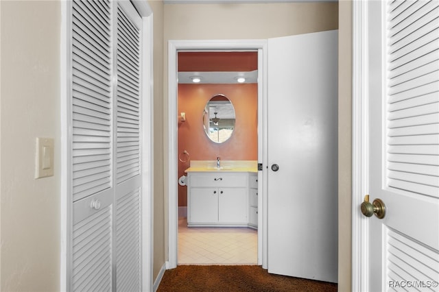 hallway with dark tile patterned floors and sink