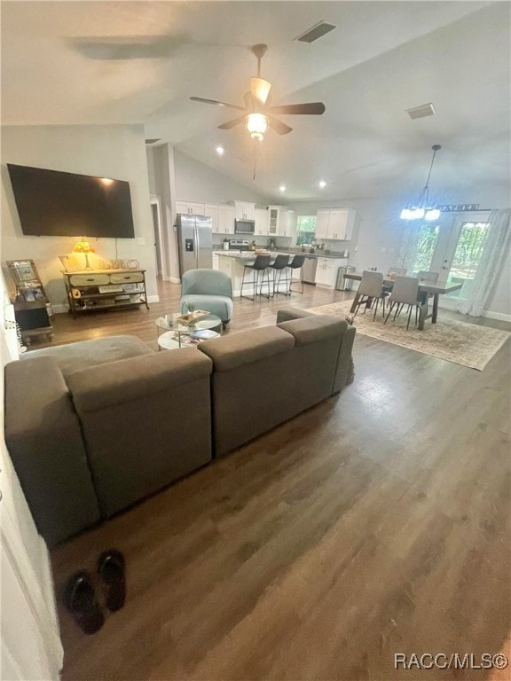 living room with french doors, ceiling fan with notable chandelier, hardwood / wood-style flooring, and lofted ceiling