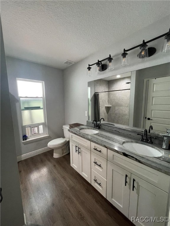 bathroom with vanity, toilet, wood-type flooring, and a textured ceiling