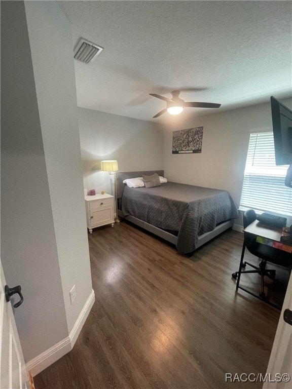 bedroom featuring a textured ceiling, ceiling fan, and dark wood-type flooring