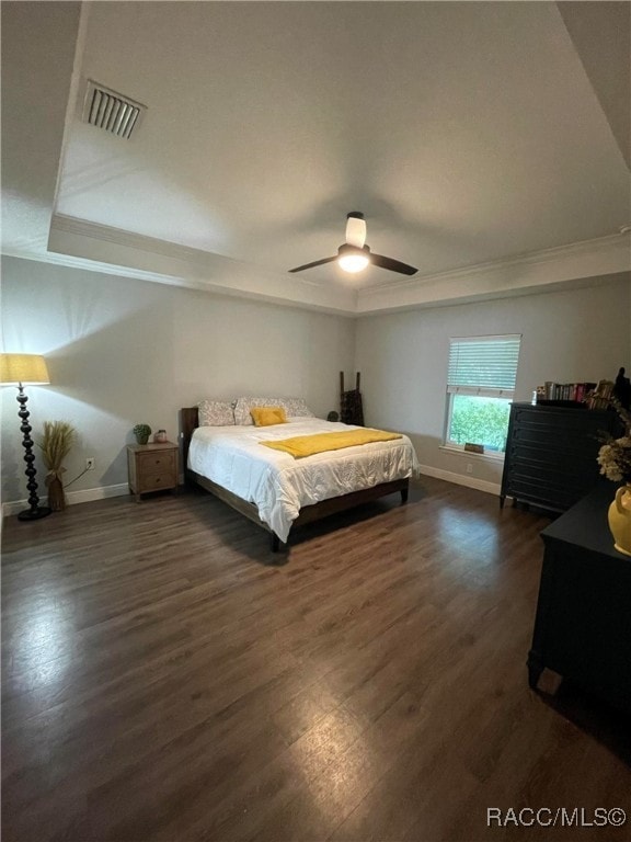 bedroom with dark hardwood / wood-style flooring, a raised ceiling, ceiling fan, and crown molding