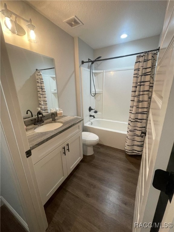 full bathroom with vanity, toilet, shower / bathtub combination with curtain, a textured ceiling, and wood-type flooring