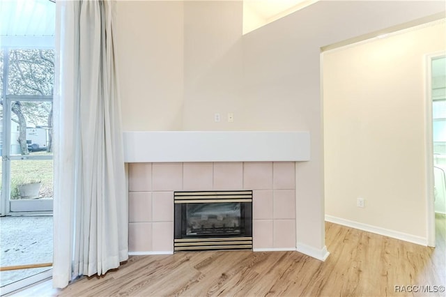 interior details with a tiled fireplace and wood-type flooring