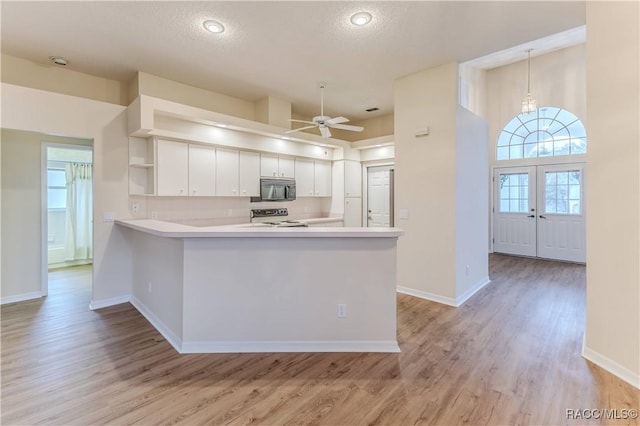 kitchen featuring white cabinetry, range, ceiling fan, kitchen peninsula, and light hardwood / wood-style flooring