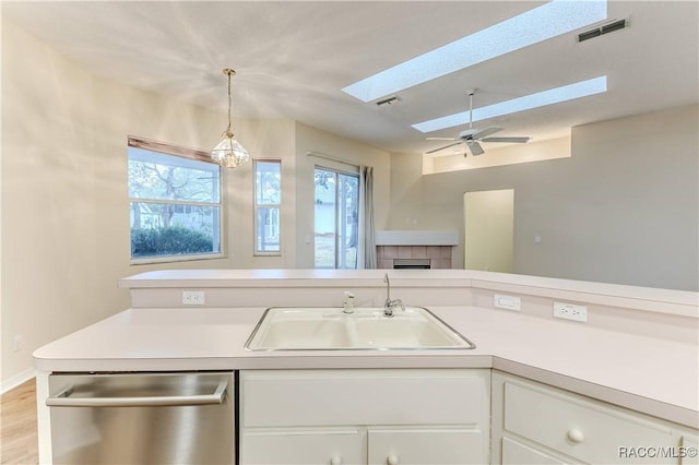 kitchen featuring sink, white cabinetry, a skylight, dishwasher, and pendant lighting