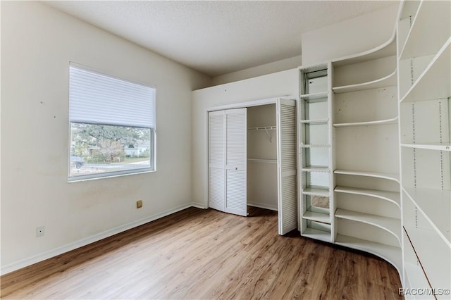 unfurnished bedroom with wood-type flooring, a closet, and a textured ceiling