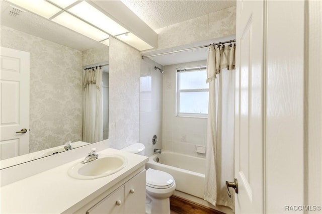 full bathroom featuring vanity, toilet, shower / bath combo with shower curtain, and a textured ceiling