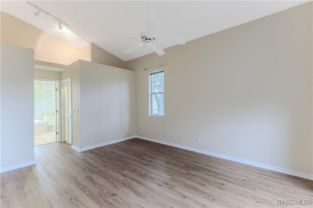 empty room featuring light hardwood / wood-style flooring, vaulted ceiling, ceiling fan, and track lighting