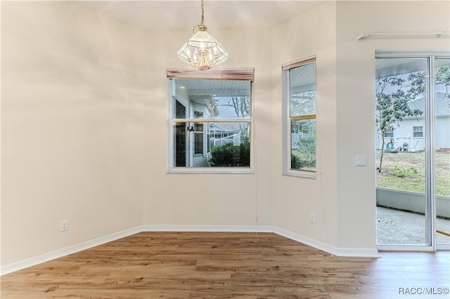 unfurnished dining area with an inviting chandelier and wood-type flooring