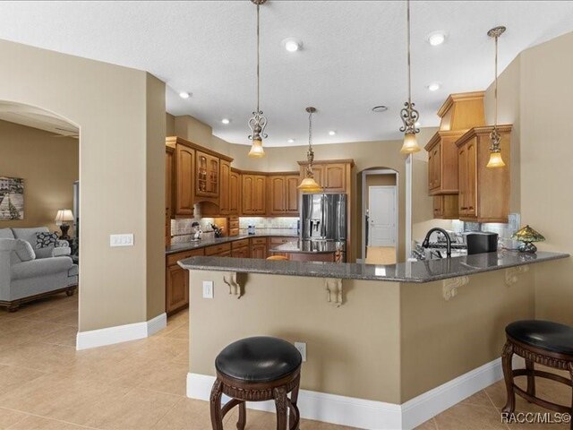 2622 N Carnoustie Loop, Lecanto, FL 34461 - kitchen featuring arched walkways, stainless steel fridge with ice dispenser, a peninsula, a kitchen bar, and light tile patterned flooring