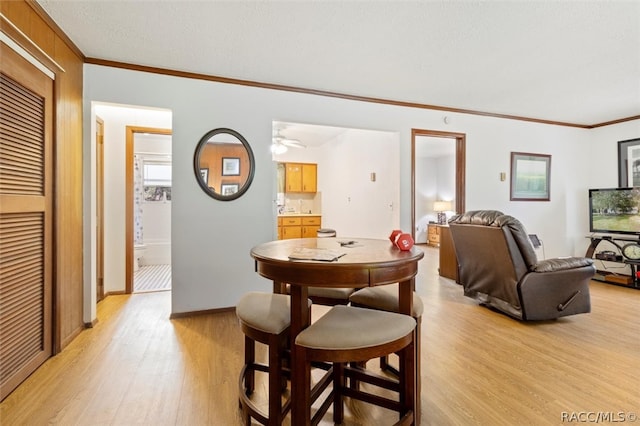 dining room with ceiling fan, ornamental molding, and light wood-type flooring