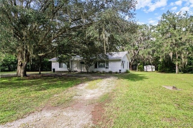 ranch-style house with a storage unit and a front lawn