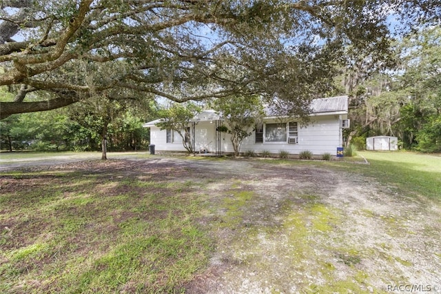 ranch-style home featuring a front yard and a storage unit